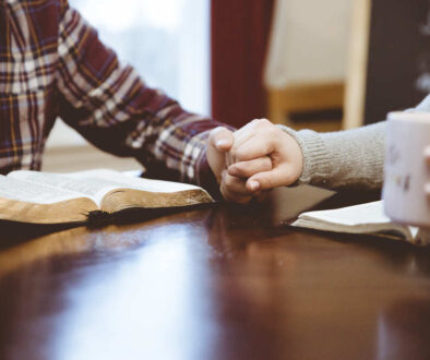 closeup-shot-couple-holding-hands-table-white-reading-their-books (1)